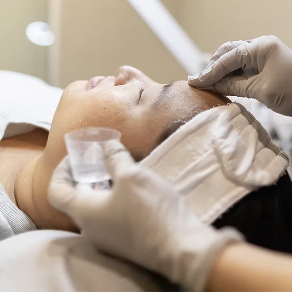 Close up on a Kalon provider applying product to the forehead of a client while they recline with their eyes closed.